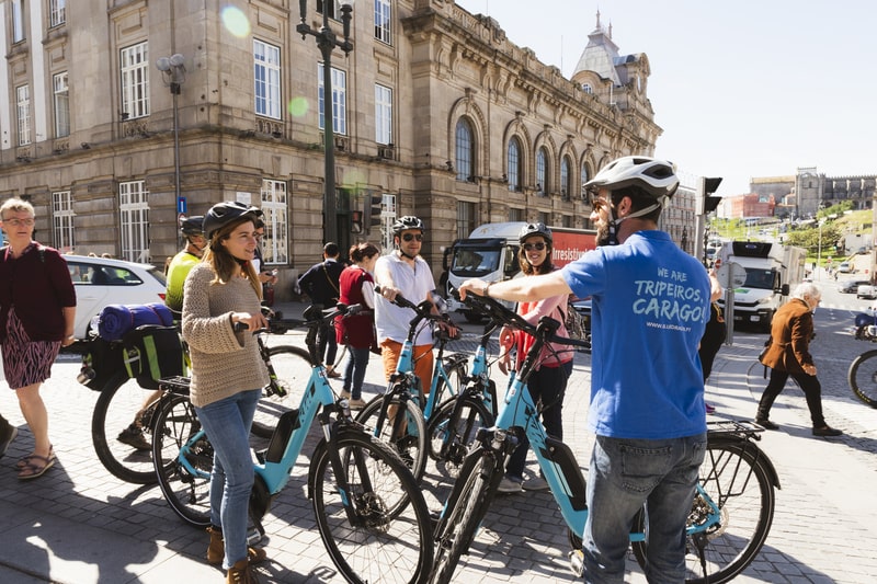 Guia a explicar a história da cidade a ciclistas no Porto Bike Tour junto à Estação de São Bento