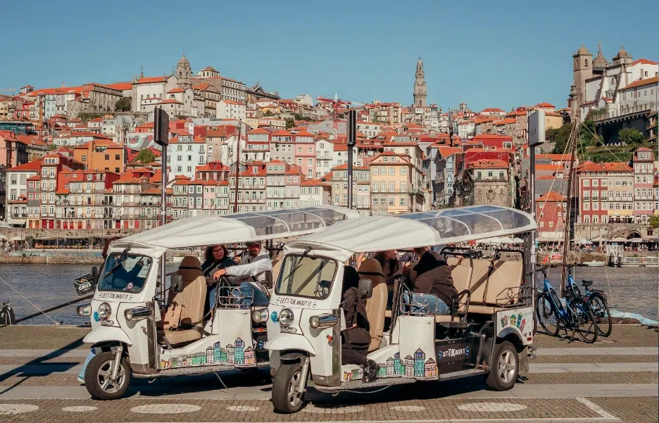 Two Tuk Tuks with the colorful Ribeira district in the background, Porto
