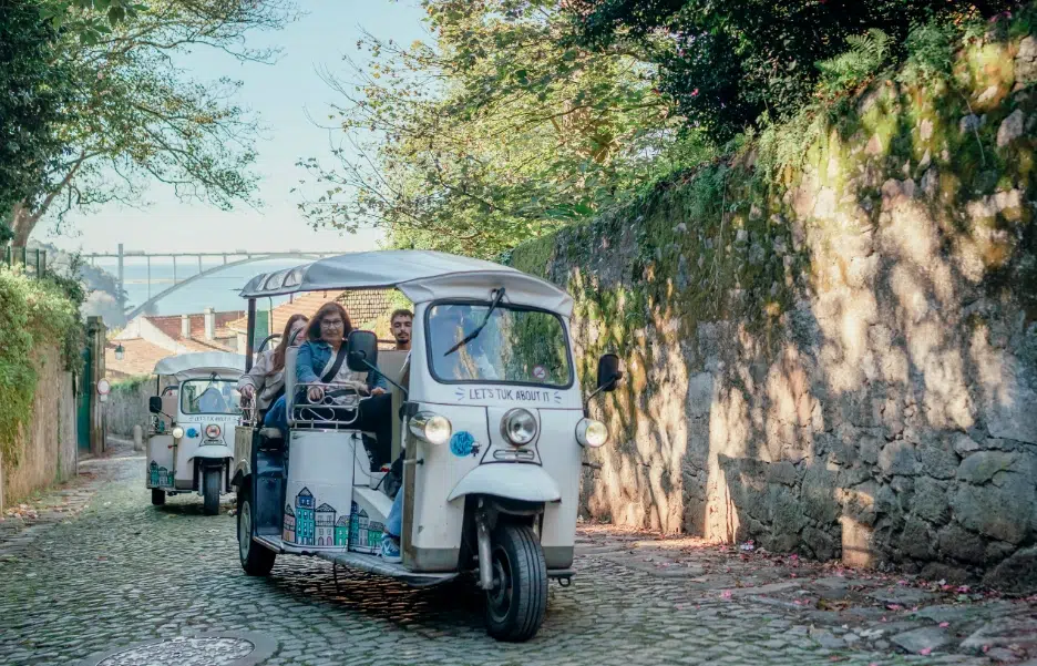 Tuk Tuk on a cobblestone street with Dom Luís I Bridge in Porto