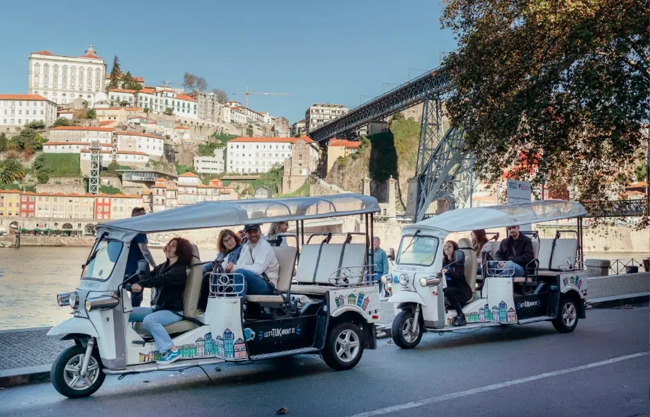 Two Tuk Tuks parked by the Douro riverside with Dom Luís I Bridge view