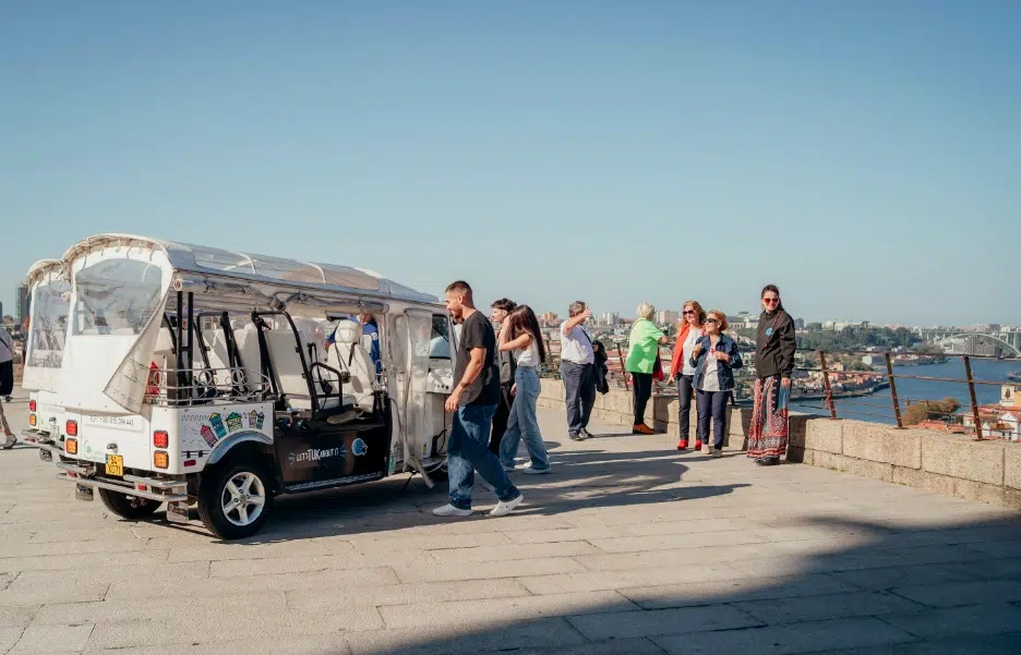 Tuk Tuk parked at a scenic viewpoint with tourists enjoying the Porto skyline