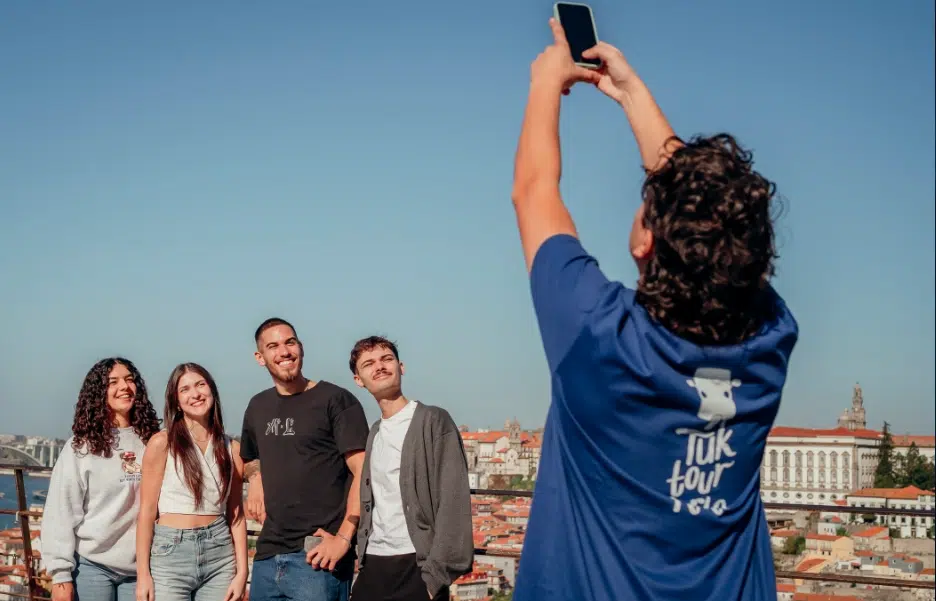Tuk Tuk guide taking a photo of happy tourists with Porto’s skyline