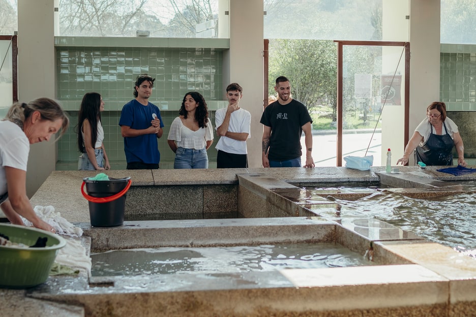 Tourists watching traditional laundry washing at a historic washhouse in Portugal