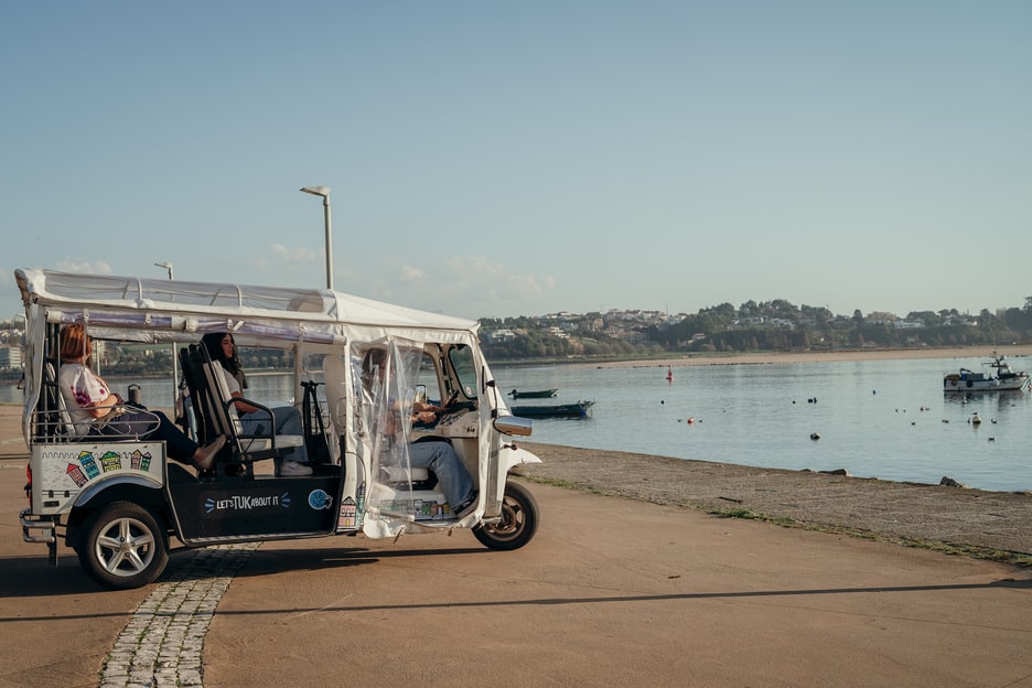 Tuk Tuk tour by the riverside with passengers enjoying the view in Porto, Portugal