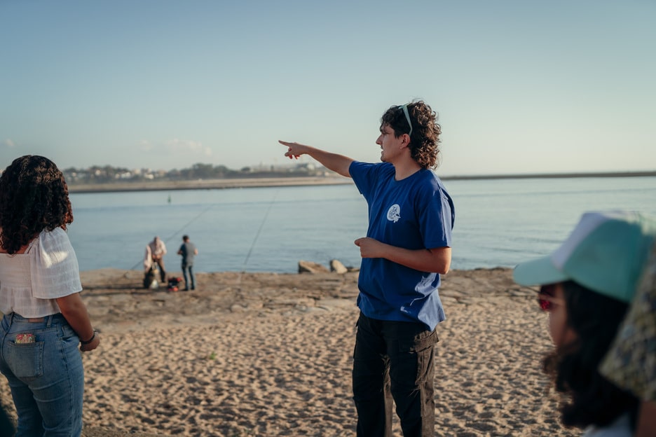 Tour guide explaining local history to visitors on a beach in Porto, Portugal