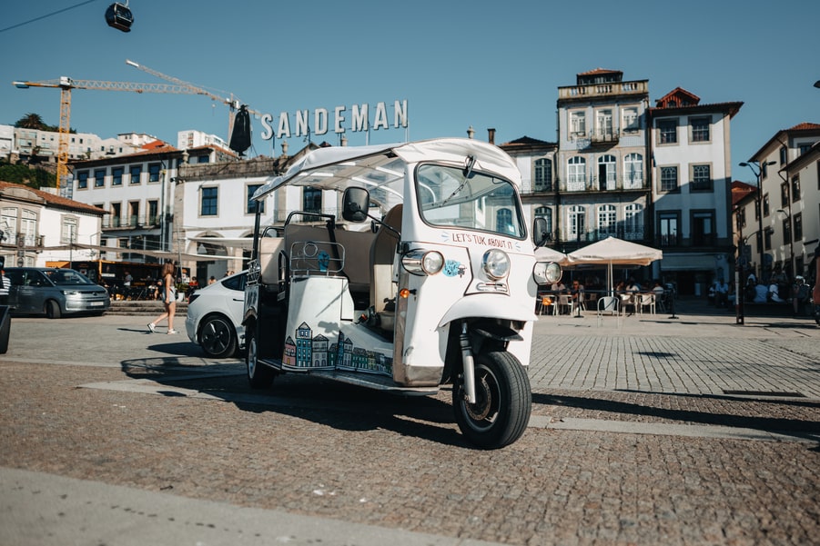 Tuk Tuk parked in front of the famous Sandeman building in Porto, Portugal
